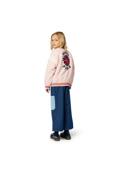 Veste bomber rose avec un motif floral et le texte "KENZO PARIS" au dos, associée à un pantalon en denim bleu à jambes larges.