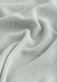 Țesătură tricotată de culoare gri deschis cu o textură subtilă în dungi, prezentând pliuri blânde și o cădere delicată. Fără modele sau accesorii vizibile.