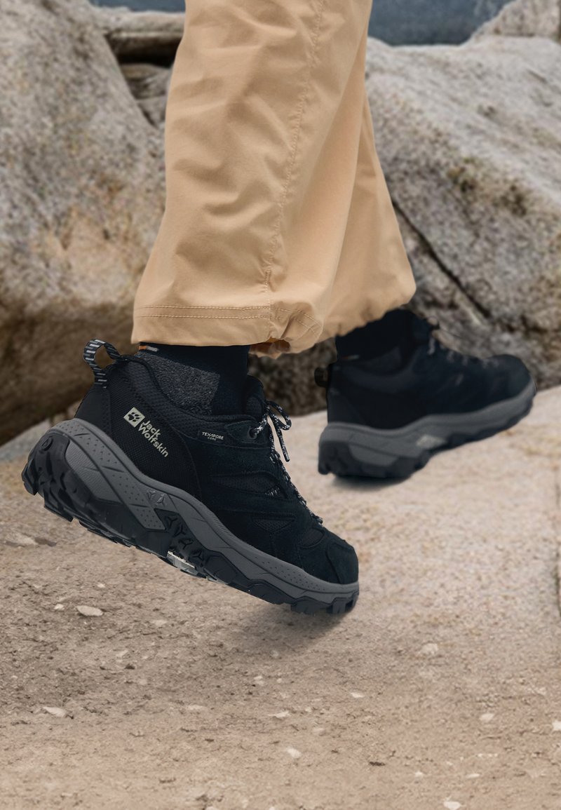 Black hiking shoes with a textured surface, cushioned midsole, and rugged outsole, featuring grey accents and lace-up design.
