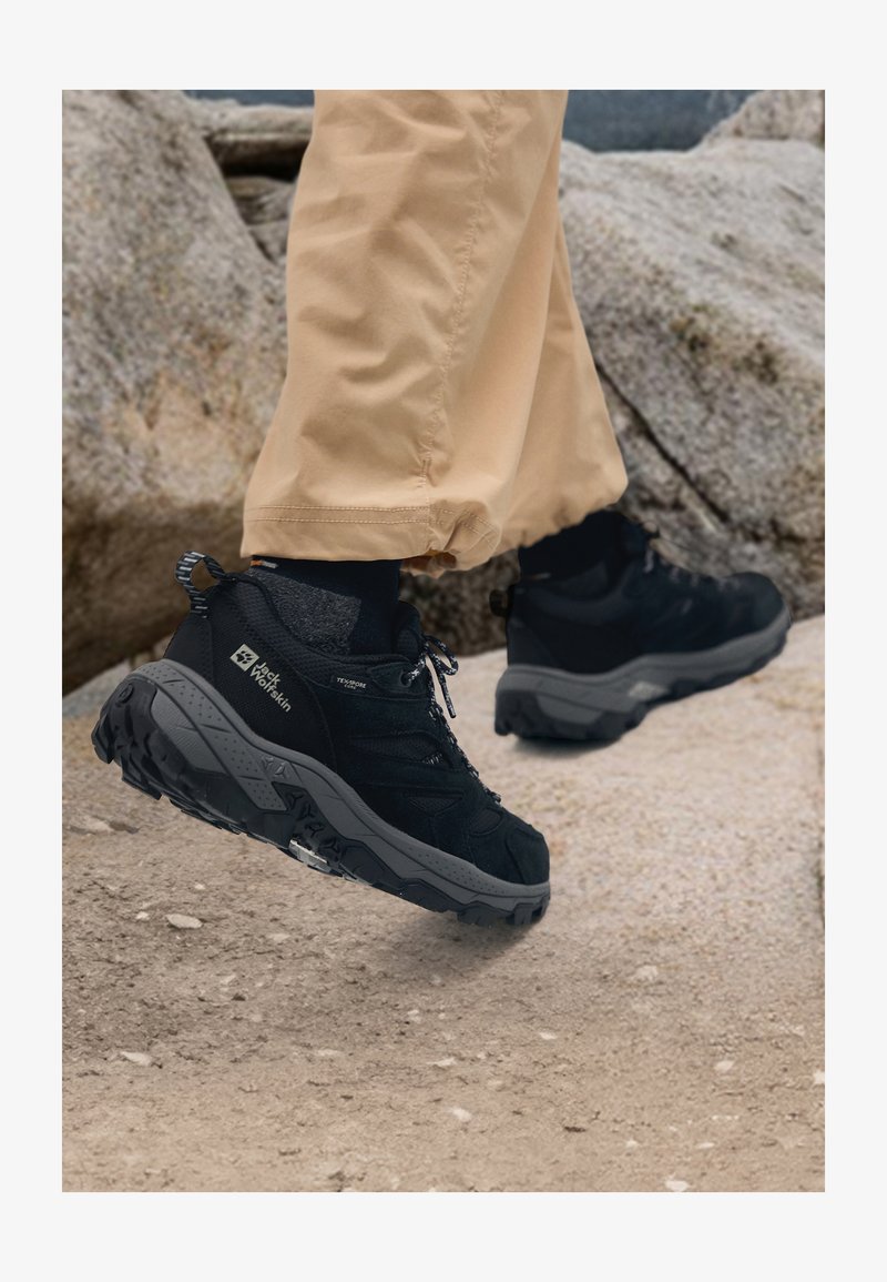 Botas de caminhada pretas com uma superfície texturizada, entressola acolchoada e sola robusta, com detalhes em cinza e design de atacadores.