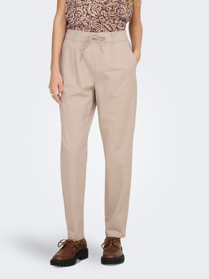 Pantalones beige de talle alto con cordón y bolsillos laterales, combinados con zapatos marrones de cordones y un top sin mangas con estampado.