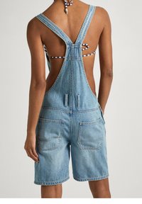 Džínové šortky s kšandami a světle modrým umytem. Mají nastavitelné kšandy, odhalený zadní díl a dvě zadní kapsy. Ležérní, volný střih.