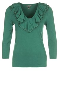 Grön långärmad topp med V-ringning och volangdetalj runt halsen, tillverkad av mjukt tyg med en slät textur.