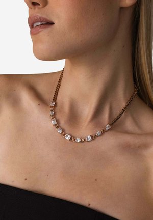 Halskette mit goldfarbener Kette, besetzt mit klaren rechteckigen und runden Kristallen, die abwechselnd aus Metallgliedern und Edelsteinen in einer symmetrischen Anordnung bestehen.