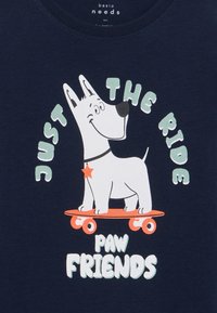 Navy blue t-shirt featuring a cartoon dog on a skateboard, with the text "JUST THE RIDE PAW FRIENDS" in playful, colorful typography.