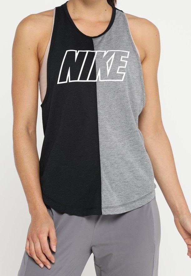 Femme portant un haut de sport sans manches, divisé verticalement en noir et gris, avec un logo Nike blanc sur la poitrine.