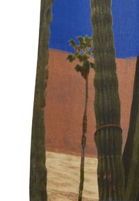 Bawełniana tkanina z motywem pustynnym. Zielone kaktusy na tle niebieskiego nieba i brązowego tła. Tekstura widoczna, z wyraźnymi szwami i ziemistymi kolorami.