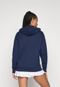 Mörkblå huva sweatshirt med en känguruficka och ribbade ärmslut. Tyget är mjukt med en slät yta, designat för komfort.