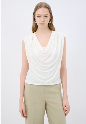 Sleevetön kermahuivi, jossa on draped-kaulus, valmistettu sileästä kankaasta. Yhdistetty vaaleanbeigeihin housuihin. Yksinkertainen muotoilu, ei näkyviä kuvioita.