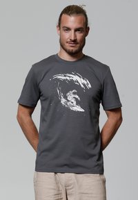 Grijze t-shirt met een witte graphic van een astronaut die op een golf surft, gemaakt van zachte katoen, met een klassieke pasvorm en korte mouwen.