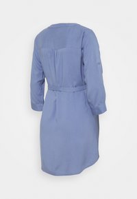 Robe bleu clair à manches longues, avec une taille ceinturée et un détail de patte de boutonnage au dos. Tissu fluide avec une coupe décontractée et un ourlet arrondi.