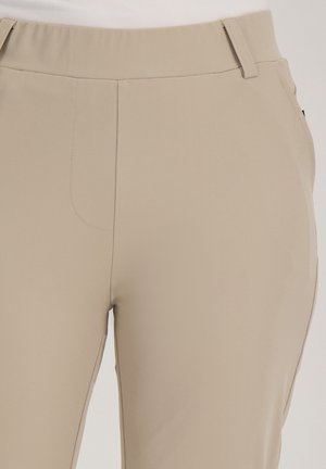 Beige hoge taillebroek met ceintuurlussen, platte voorkant, zichtbare naaddetails en een getailleerde pasvorm bij de heupen en dijen.