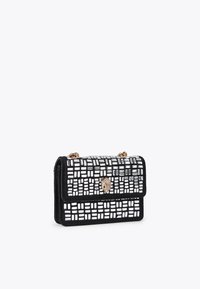 Borsa a mano con motivo in bianco e nero, superficie testurizzata, hardware dorato e chiusura a scatto. Dotata di una tracolla a catena.
