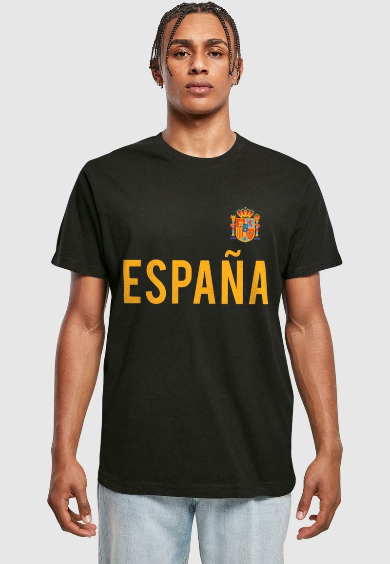 Juodas medvilnės marškinėliai su žodžiu "ESPAÑA" ryškiai geltonu šriftu ir spalvingu Ispanijos herbu kairėje krūtinės pusėje. Trumpomis rankovėmis.