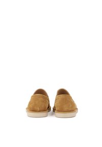 Scarpe slip-on in suede marrone con retro arrotondato, superficie testurizzata e suola in gomma chiara, caratterizzate da dettagli di cucitura minimi.