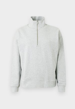 Hanorac gri deschis, cu guler înalt și fermoar pe jumătate, cu mâneci lungi și un logo brodat subtil pe piept. Textură moale.