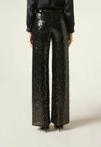 Pantalons larges en sequins noirs avec une taille haute et une texture lisse et brillante, avec une coupe droite et un détail d'ourlet négligé.