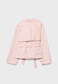 Světlá růžová krátká bunda s dlouhými rukávy, límcem a připevněnými páskovými popruhy, zobrazená zezadu na šedém pozadí.