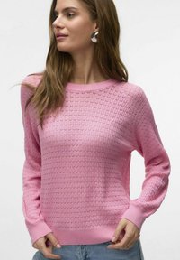 Svetlo roza pletena jopica s teksturiranim vzorcem, okroglim izrezom in dolgimi rokavi. Rebrasti manšeti in rob. Prilagojena casual kroju. Lahka material.
