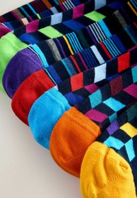 Sokid erksate värviliste geomeetriliste mustritega, millel on triibud, ševroonid ja plokid erksates värvides, sealhulgas roheline, lilla, punane, sinine, oranž ja kollane.