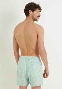 Șorturi de baie aqua blue cu un model repetitiv de picături colorate, talie elastică și un buzunar la spate.