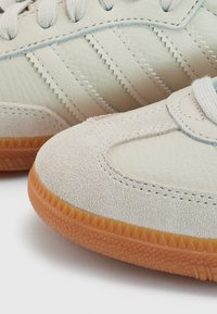 Lichtgekleurde sneakers van leer en suede, met drie gestreepte accenten, een ronde neus en een gestructureerde rubberen outsole.