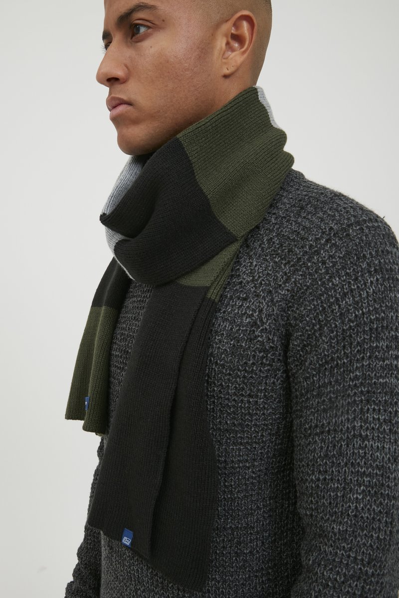 Strickschal mit Blockdesign in Schwarz, Olivgrün und Grau. Hergestellt aus weichem Material, mit gerippter Textur und gesäumten Kanten.