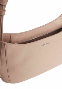 Sac à épaule Calvin Klein en matériau texturé rose doux avec un motif de logo, fermeture éclair et bandoulière tressée. Design lisse et minimal.