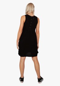 Vestido negro sin mangas con un top ajustado y falda acampanada, que cuenta con un detalle de botones en la parte trasera y una tela ligera.