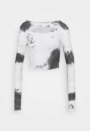 Biały krótki top z długim rękawem z czarnym wzorem tie-dye i poziomym wycięciem blisko dekoltu.