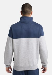 Pullover-Sweatshirt in Marineblau und Grau. Hoher Kragen, mehrfarbiges Design, weiche Textur, mit gerippten Bündchen und Saum. Enthält ein Rückenpatch.