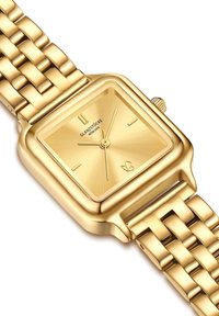 Kuldne ruudukujuline kell, millel on tekstureeritud kellanägu, kuldsed tunni markerid ja käed ning ühendatud käevõru rihm. Kellale on lisatud bränding.