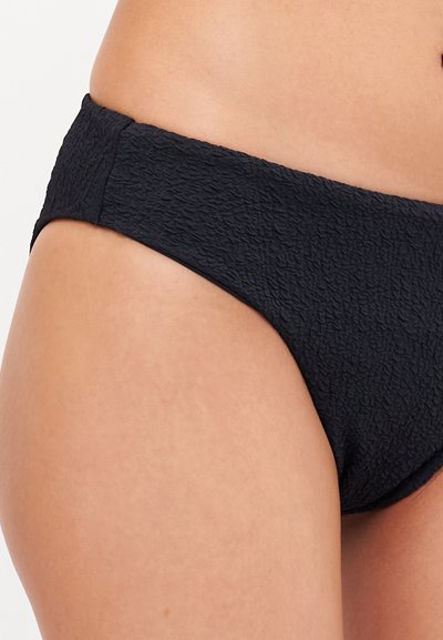Melnas bikini apakšda ar struktūrētu audumu, ar vidēju vidukļa līniju un vienkāršām, tīrām līnijām. Gluda apdare bez rotājumiem.