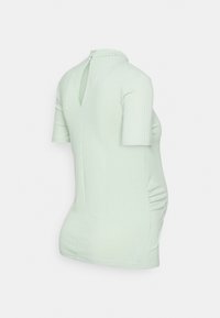 Top amarelo-claro de malha com mangas curtas, apresentando um design de abertura nas costas e detalhe de franzido na lateral para um ajuste justo.