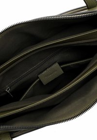 Olijfgroene tasinterieur met meerdere vakken, een gladde stofvoering en een merketiket. Ritszakken voor veilige opslag.