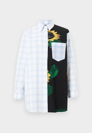 Chemise à manches longues boutonnée avec un motif à carreaux blancs et bleu clair d'un côté, noire avec une grande impression de tournesol jaune de l'autre.
