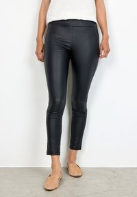 Leggings neri aderenti realizzati in un materiale lucido e elasticizzato. Lunghezza alla caviglia con una consistenza liscia e una cintura ampia e confortevole.