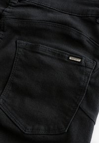 Czarne dżinsy z denimu z tylną kieszenią ozdobioną metalową metką „NEXT”, gładką fakturą i płaskimi szwami.