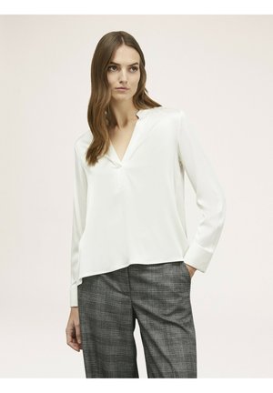 Witte lange mouwen blouse met een V-hals en subtiele knoopsluiting. Zachte stof met een gladde afwerking, gecombineerd met grijze geruite broek.