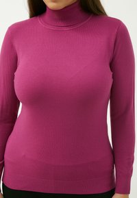 Engerschnittiger Rollkragenpullover in leuchtendem Pink, aus weichem Strickstoff gefertigt. Verfügt über lange Ärmel und gerippte Akzente am Kragen und Saum.
