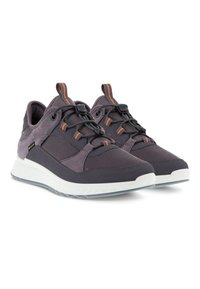 Scarpe da ginnastica viola realizzate con materiali in rete e suede, dettagli testurizzati, lacci elastici, rifiniture riflettenti e una suola bianca imbottita.