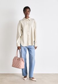 Beige button-up shirt, light blue jeans, and a pink quilted handbag. The shirt has a collar and long sleeves; the bag features dual handles.