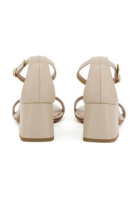 Sandali beige con tacco largo, cinturino alla caviglia regolabile e design minimalista. Texture liscia e schiena aperta.