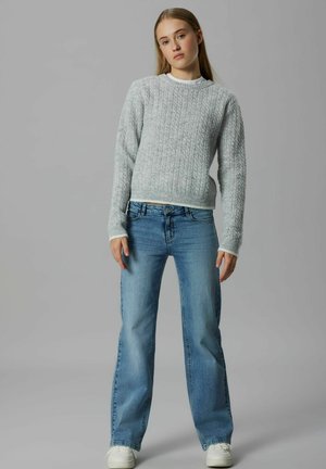 Pulover din tricot cu țesătură în relief, de culoare gri deschis, cu mâneci lungi, asortat cu blugi drepți de culoare albastră deschisă și sneakers albi. Design simplu și modern.