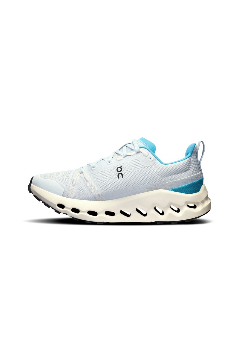 Hellblaues Sportschuhmodell mit einem atmungsaktiven Mesh-Obermaterial, weißer Dämpfungssohle, ausgeprägten Ausschnitten und einem blauen Akzent an der Ferse.