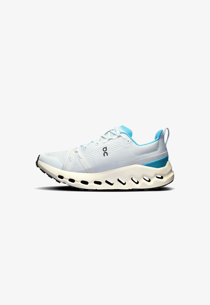 Hellblaues Sportschuhmodell mit einem atmungsaktiven Mesh-Obermaterial, weißer Dämpfungssohle, ausgeprägten Ausschnitten und einem blauen Akzent an der Ferse.