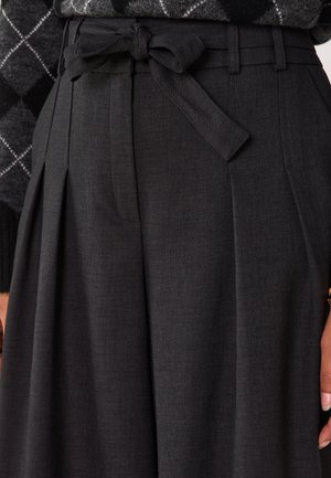 Pantaloni pieghettati grigio scuro realizzati in tessuto strutturato, con vita annodata e tasche laterali, dall'aspetto sartoriale e definito.