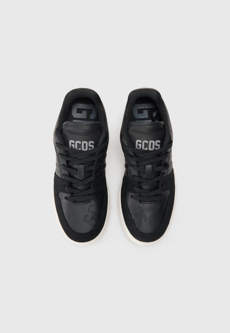 Black sneakers with a smooth leather and textile mix, featuring laces, and a white rubber sole. "GCDS" logo on the tongue and side.