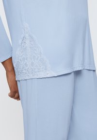 Ljusblått loungewear-set med spetsdetalj på sidan. Materialet är mjukt med en jämn yta och avslappnad passform.