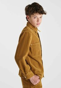Bruine corduroy shirt met een kraag en een enkele borstzak. Heeft een verticale ribbelstructuur en knoopmanchetten.